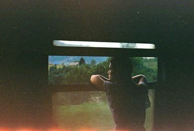 Rear view of person standing by window