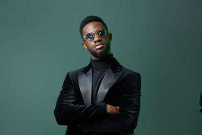 Portrait of young man standing against black background