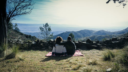 Rear view of people looking at mountains against sky