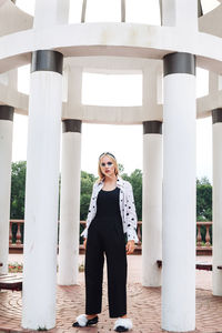 Portrait of young woman standing against built structure