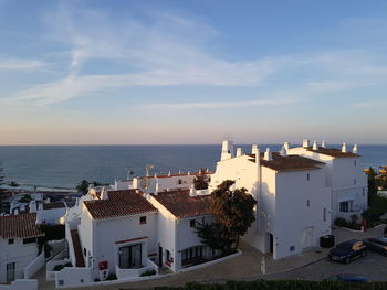 Buildings in town by sea against sky