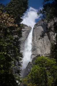 Scenic view of waterfall in forest against sky