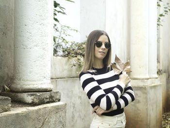 Portrait of young woman standing against wall