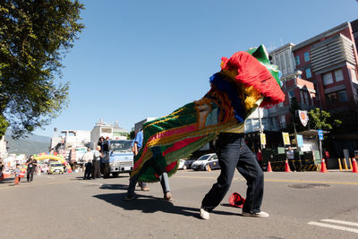 People walking on road in city against clear sky