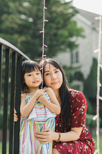 Portrait of mother and daughter by railings