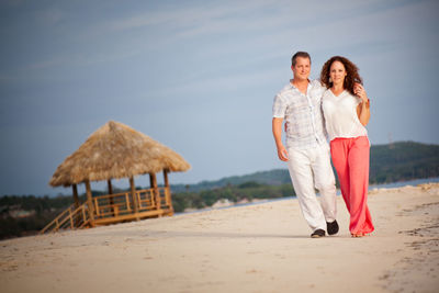 Full length of mature couple walking at beach