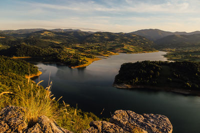 Scenic view of lake by mountains against sky