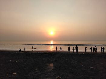 Silhouette people on beach during sunrise at batu karas beach