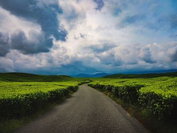 Road amidst field against sky