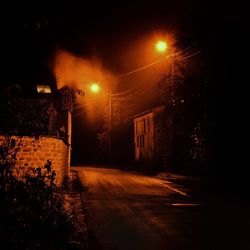 Illuminated street amidst buildings at night