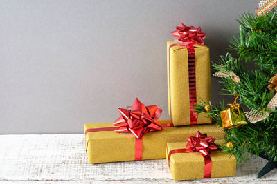 Close-up of christmas tree and presents against gray wall