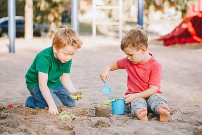 Children sitting in sandbox playing with beach toys. summer outdoor activity for kids. leisure time 