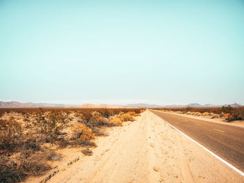 Road amidst desert against clear sky