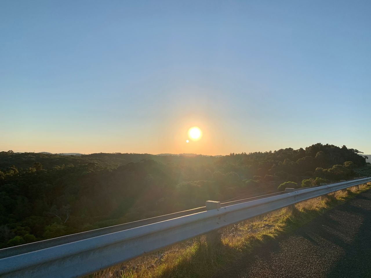 sky, horizon, morning, road, nature, sun, transportation, sunlight, landscape, sunrise, environment, scenics - nature, dawn, beauty in nature, tranquility, no people, hill, highway, tranquil scene, plant, lens flare, land, travel, clear sky, non-urban scene, sunbeam, outdoors, sunny, idyllic, tree, blue, light, rural scene, travel destinations, copy space, country road, infrastructure, the way forward, street, cloud, twilight, water, field