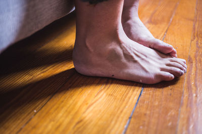 Low section of person legs on hardwood floor at home