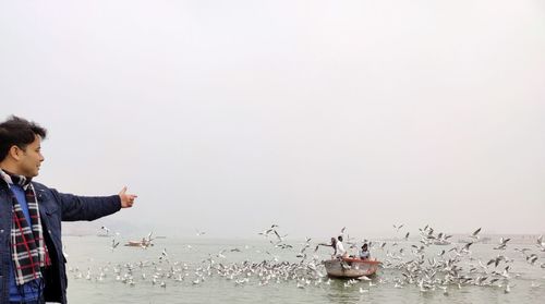 Side view of man standing in sea against clear sky