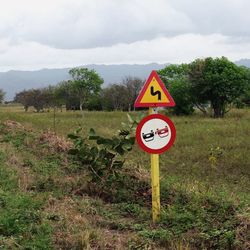 Road sign on grassy field against sky