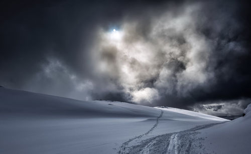 Scenic view of snowcapped mountain and ski tracks with a full moonagainst sky