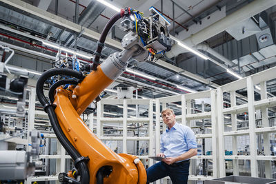 Businessman examining industrial robot in a factory