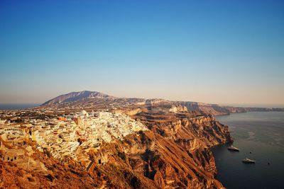 Scenic view of sea and mountains against clear blue sky