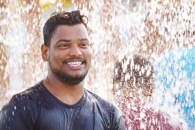 Water splashing on smiling young man 