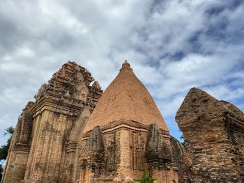 Low angle view of old temple against cloudy sky