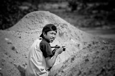 Man crouching with camera amidst piles of sand