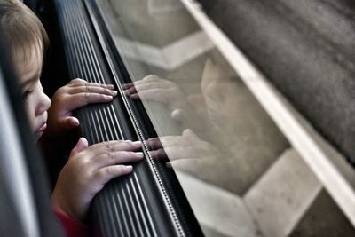 Cropped image of toddler looking through car window