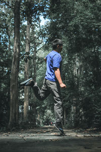 Rear view of man jumping in forest