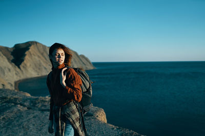 Woman standing by sea against sky