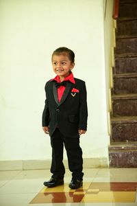Portrait of smiling boy standing against wall
