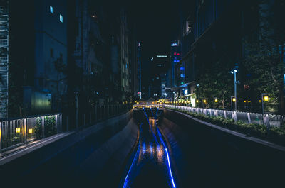 Illuminated river amidst buildings in city at night