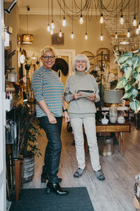 Happy senior female entrepreneurs standing together at home interior store