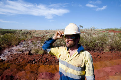 Miner wearing hardhat while standing on field