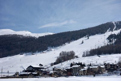 Scenic view of snow covered landscape and houses against sky