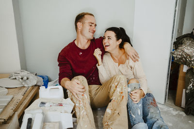 Cheerful couple sitting together in room while renovating home