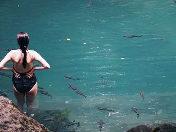 High angle view of woman standing in sea on sunny day