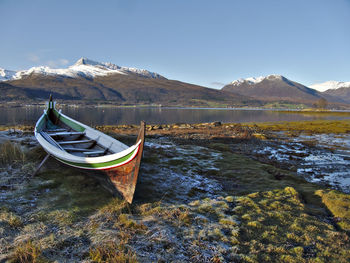 Boat moored in lake against sky during winter