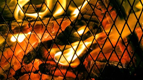 Low angle view of chainlink fence against sky during sunset