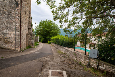 Road amidst trees and buildings against sky