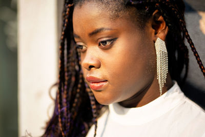 Close-up of young woman looking away while standing against wall