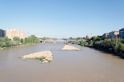 Scenic view of river by city against clear sky