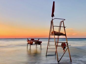 Lifeguard hut on beach against sky during sunset