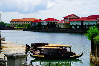 Boats moored on river by buildings against sky