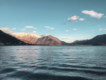 Scenic view of sea by mountains against sky