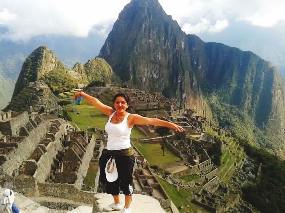 FULL LENGTH OF WOMAN SMILING AGAINST MOUNTAINS