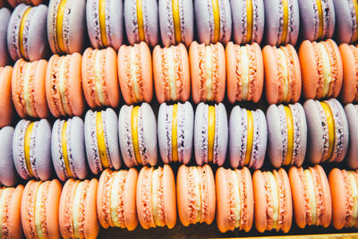 Macaroons of purple and coral color with yellow cream in a box close-up