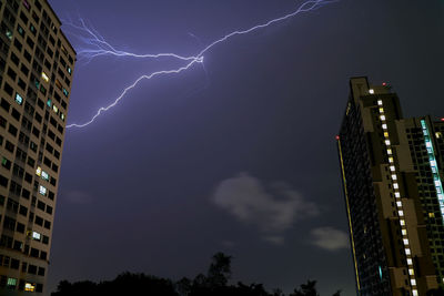 The real lightning flashing in night sky over high buildings of bangkok, thailand