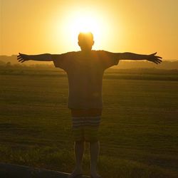 Silhouette of woman jumping on landscape at sunset