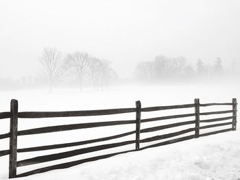 Wooden fence on snow covered landscape
